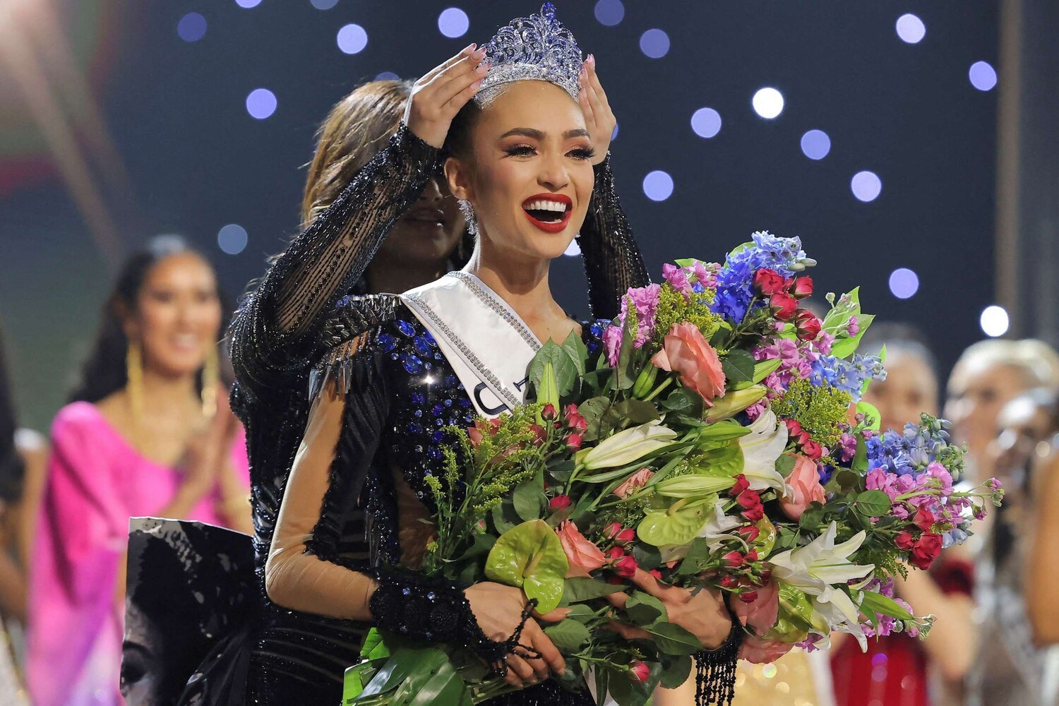 R'Bonney Gabriel being crowned Miss Universe 2022, wearing the same black beaded gown from her GM Custom Clothier fitting